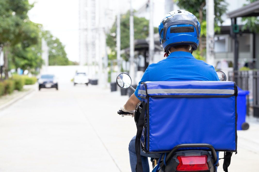 repartidor-uniforme-azul-montando-motocicleta-caja-entrega