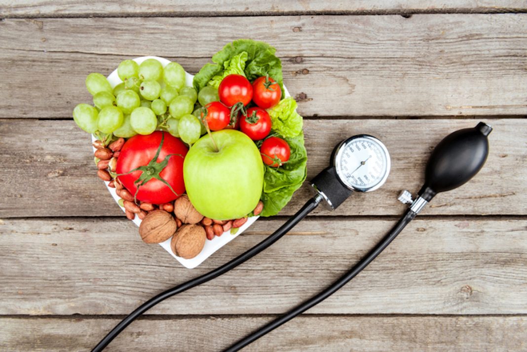 top view of fresh various vegetables, fruits and blood pressure gauge on wooden surface, healthy eating concept